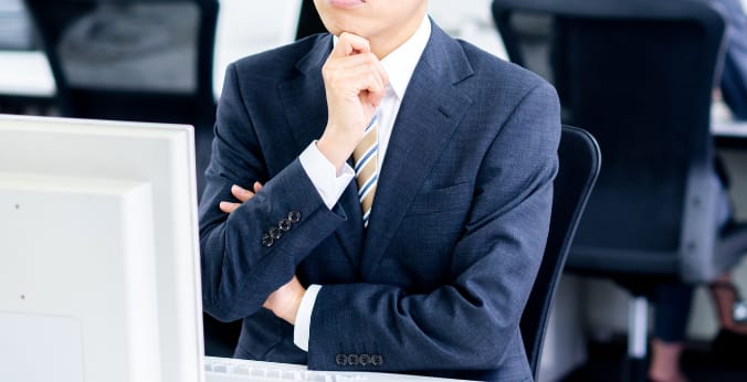 顎に手を当て考えるビジネスマンの写真